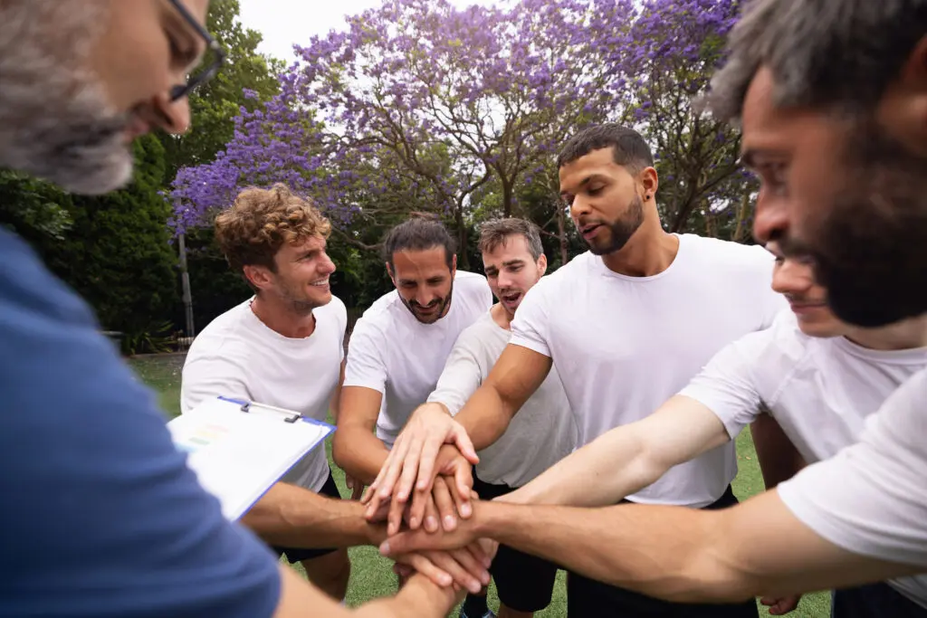 A group of friends stacking hands outdoors showing unity.