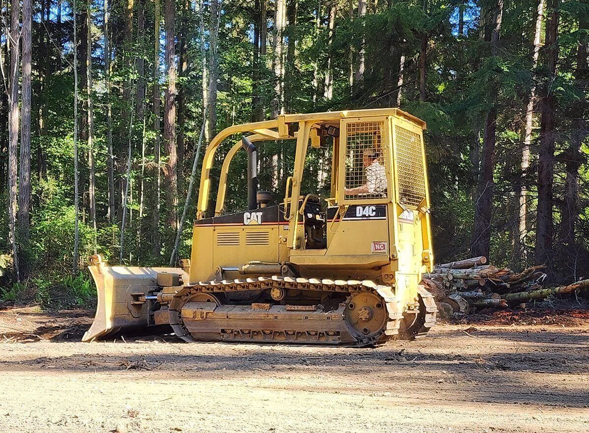 Bulldozer clearing land in forest area.